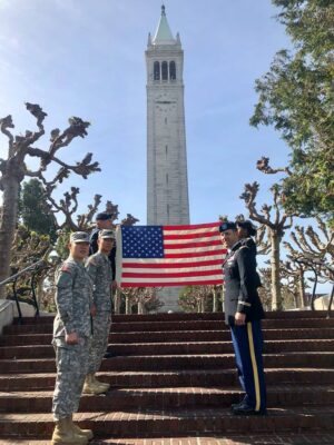cadets holding american flag near steps of sather tower