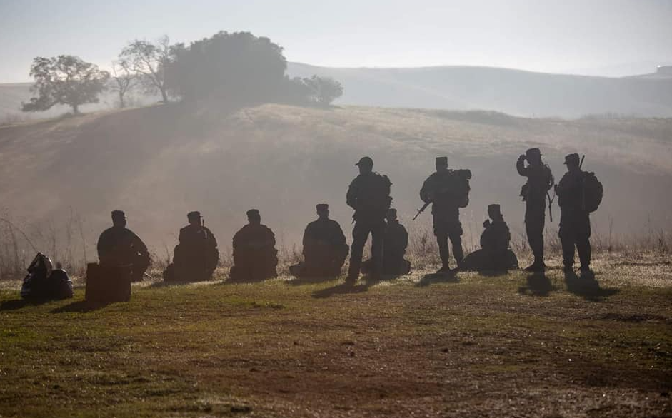 silhouette of army cadets on top of a hill with gear